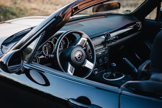 Close-up of a sleek convertible interior highlighting the steering wheel and dashboard.