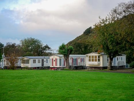 Mobile homes surrounded by lush greenery and hills, depicting a serene countryside getaway.